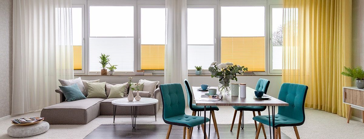 Salón y comedor luminosos con grandes ventanas y estores plisados de protección solar
