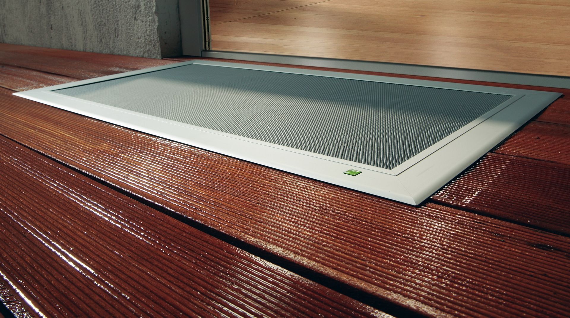 Terresa Lichtschachtabdeckung von Neher, flächenbündig in eine Holzterrasse integriert und begehbar ausgeführt.