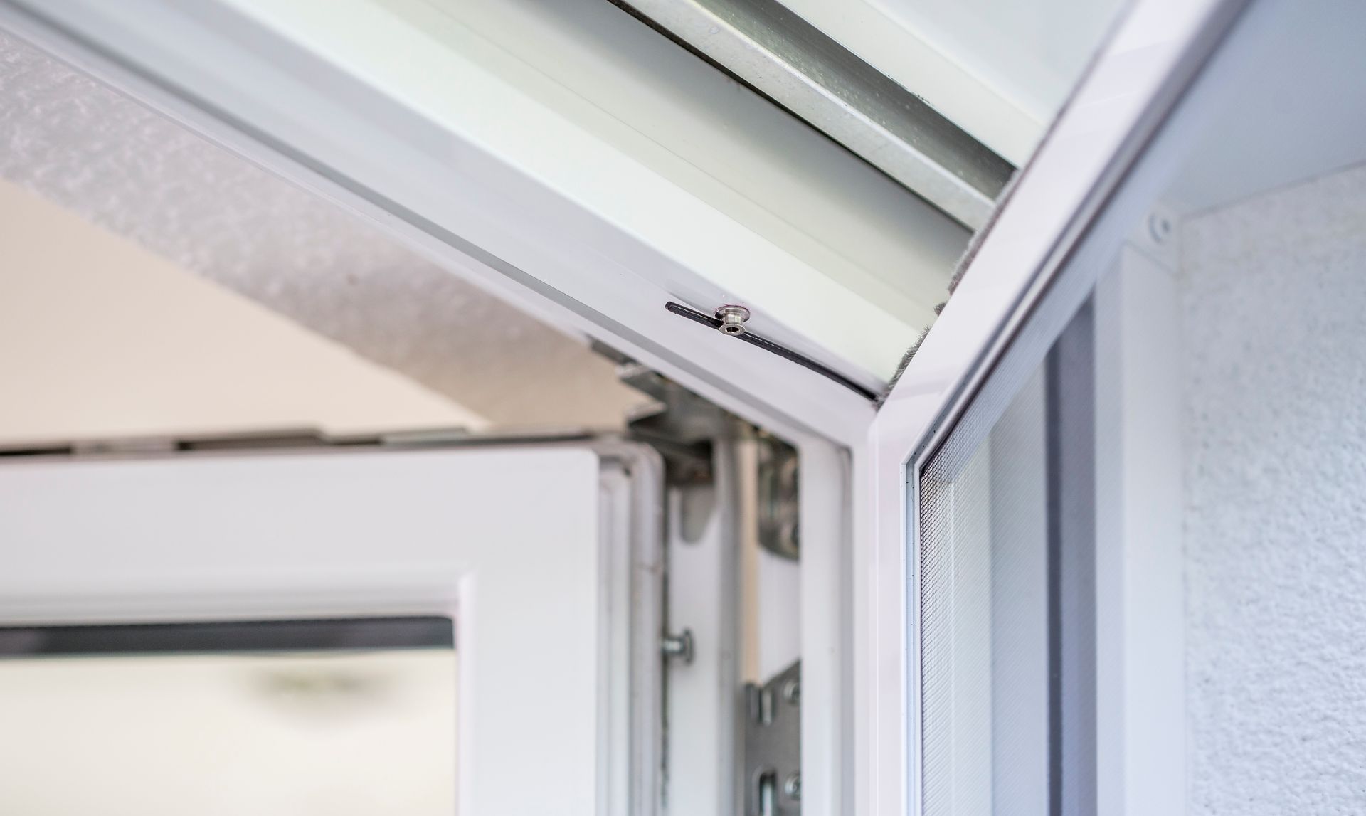 Detailed view of the integrated spring mechanism of an ISK Systeme insect screen swing door for automatic, quiet closing.