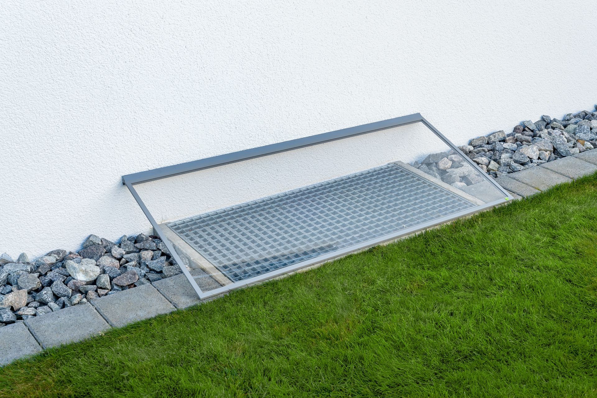 Regenschutzabdeckung RESI schräg an der Hauswand montiert – zuverlässiger Schutz für Lichtschacht vor Regen und Schmutz