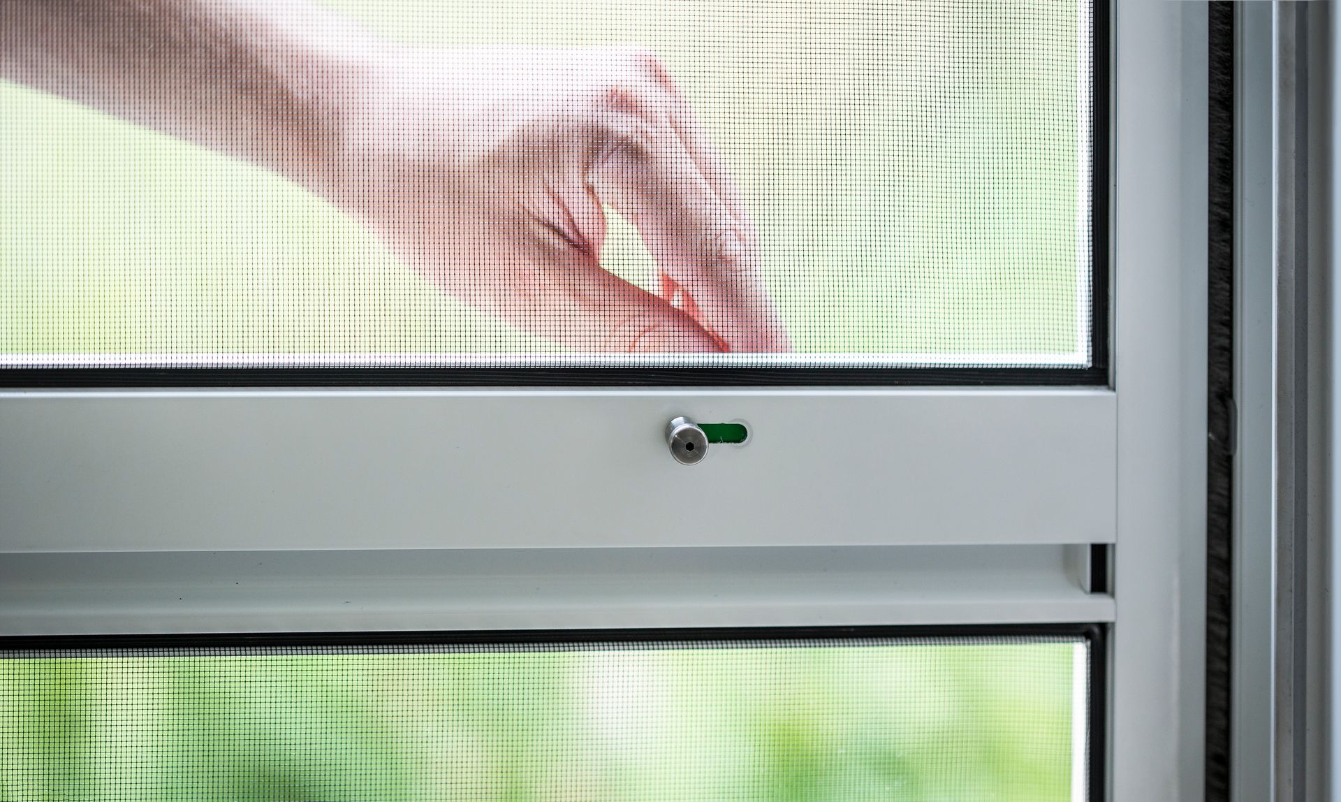 Detailed view of the integrated sliding lock of an ISK Systeme insect screen swing door for secure fixing in the closed position.