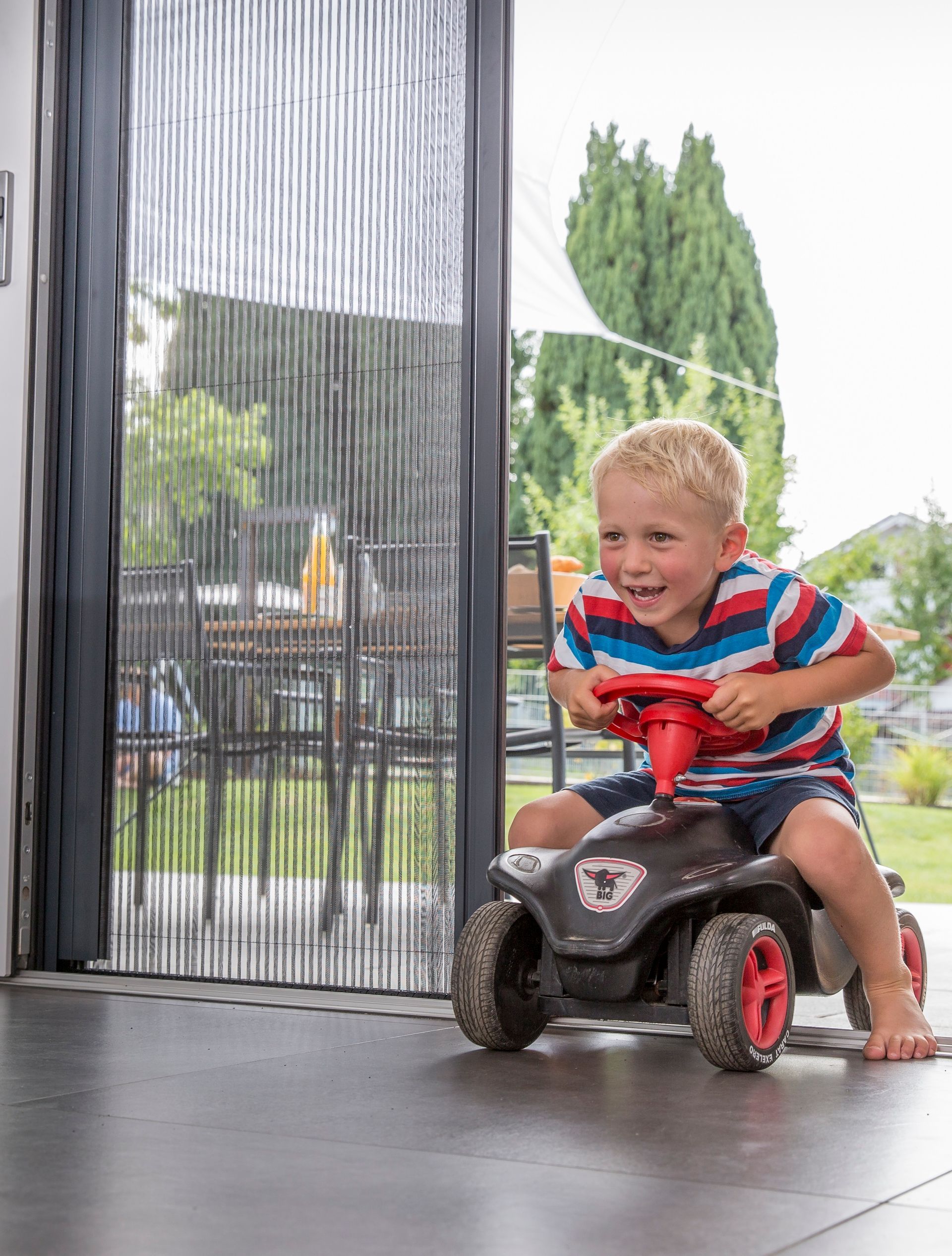 Puerta mosquitera plisada de ISK Systeme instalada en acceso a terraza – sistema plisado Neher resistente, apto para niños, que permite ventilación natural y protección eficaz contra insectos.
