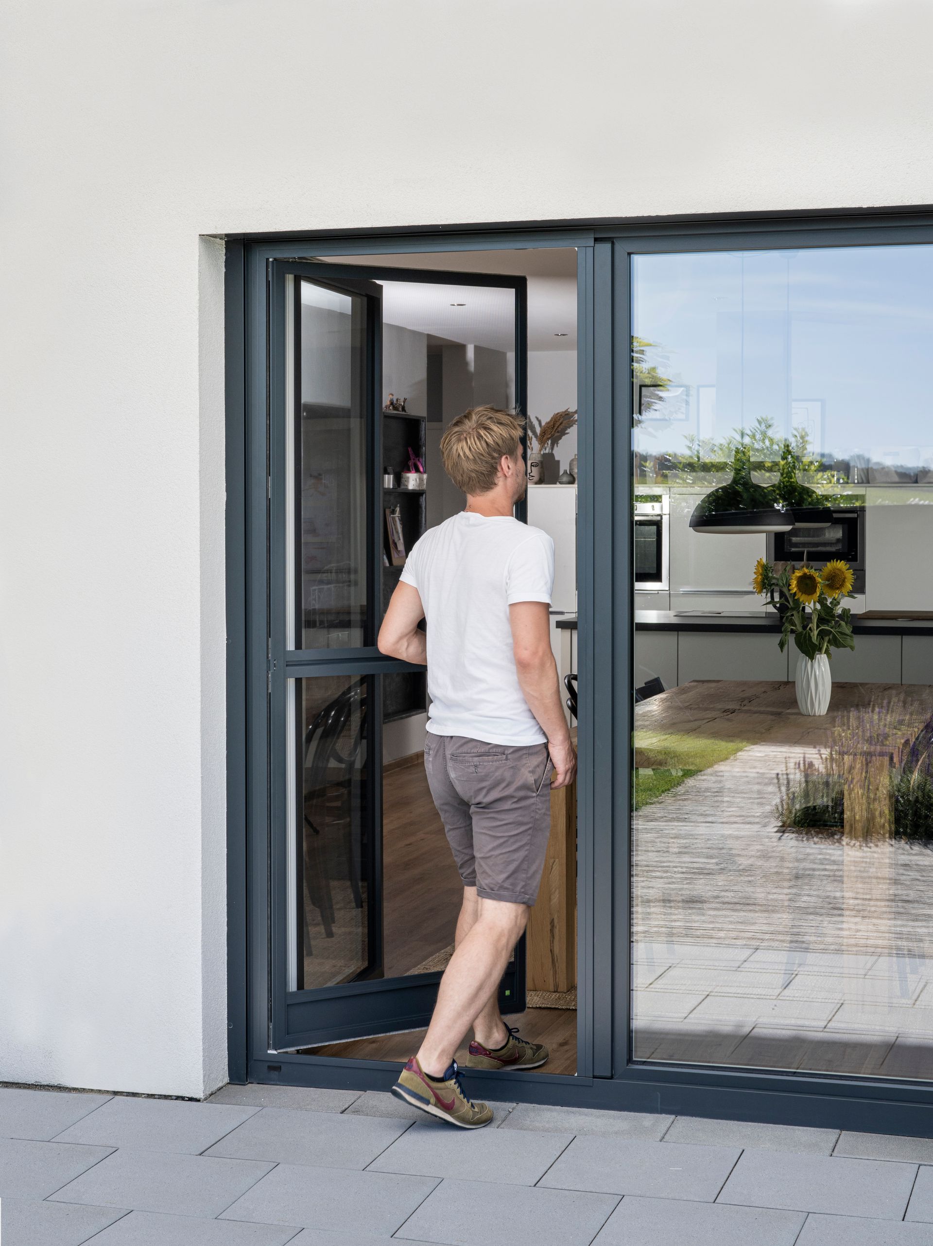 Maßgefertigte ISK Systeme Insektenschutz-Pendeltür an einer Terrassentür, komfortabler Durchgang bei geöffnetem Türflügel.