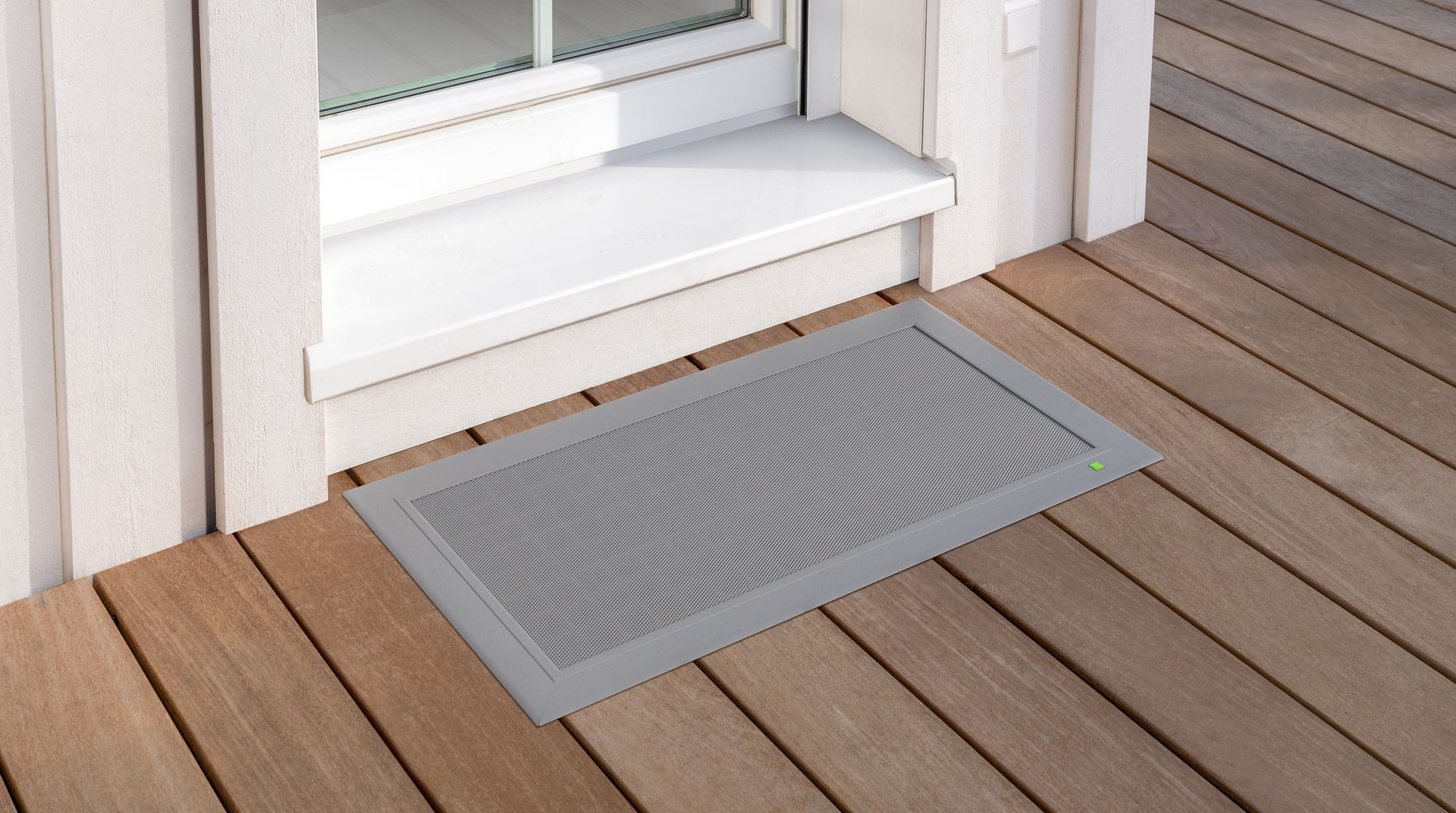Terresa Lichtschachtabdeckung von Neher, flächenbündig vor einer Terrassentür in eine Holzterrasse integriert und begehbar.