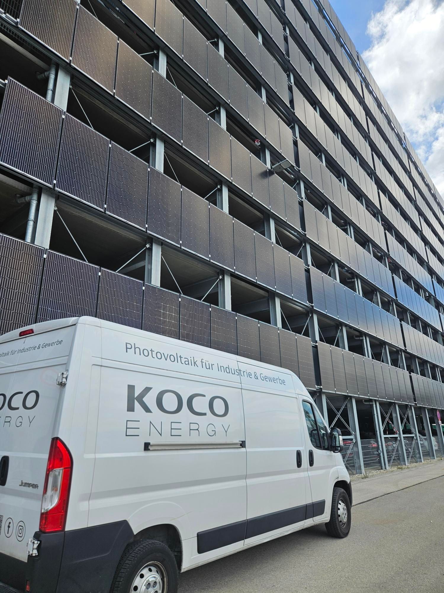 Photovoltaik-Fassade eines Parkhauses mit einem Auto der KOCOEnergy AG davor