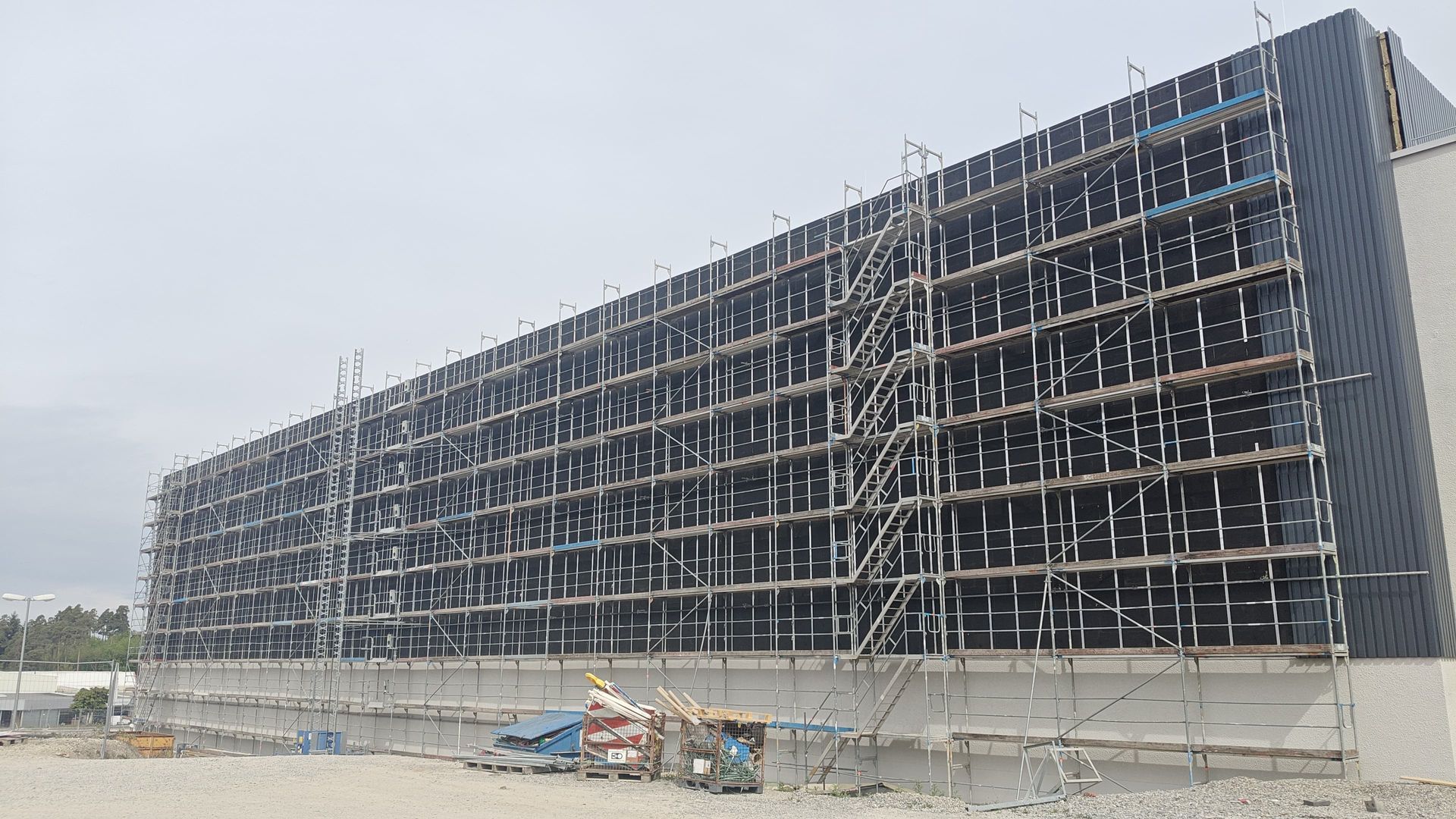 Industriegebäude mit eingerüsteter Fassade und integrierten Photovoltaik-Modulen während der Montage