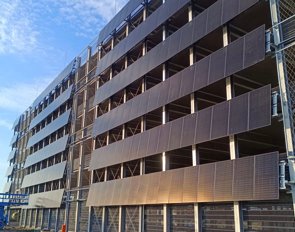 Parkhaus in Würselen mit geneigter PV-Fassade auf mehreren Ebenen bei Sonnenlicht mit dunklen Solarm