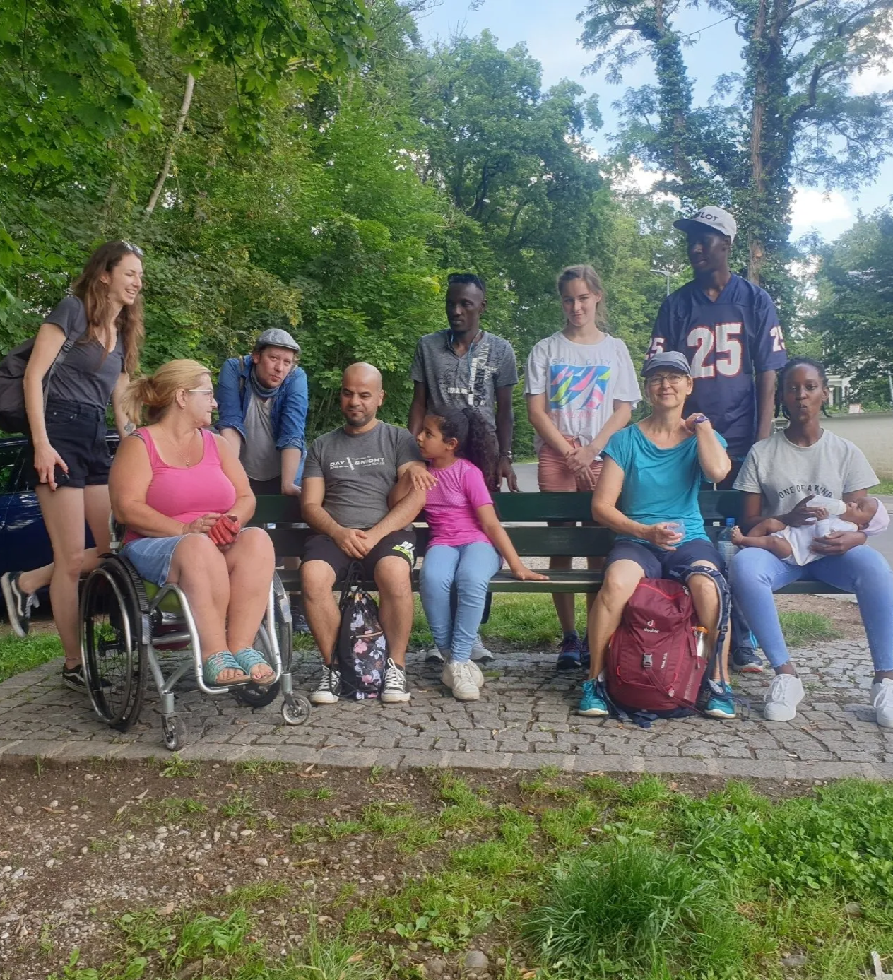 Gruppenteilnehmer der Isarwanderung sitzen auf einer Bank