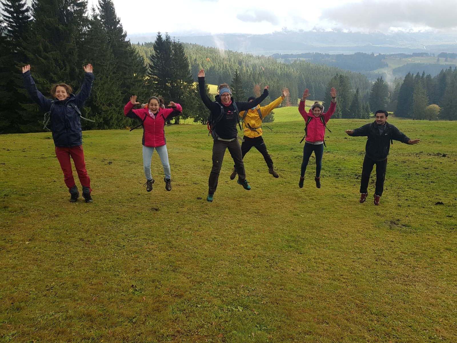 Die Wanderer springen alle gleichzeitig in die Luft und freuen sich über die Sonnenstrahlen.