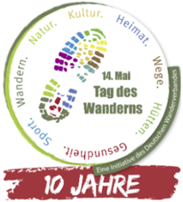 Logo mit zwei bunten Fußabdrücken und dem Text '14. Mai Tag des Wanderns' umgeben von Begriffen wie 'Wandern', 'Natur', 'Kultur', 'Heimat', 'Wege', 'Hütten', 'Gesundheit', 'Sport' sowie einem roten Banner mit '10 JAHRE'