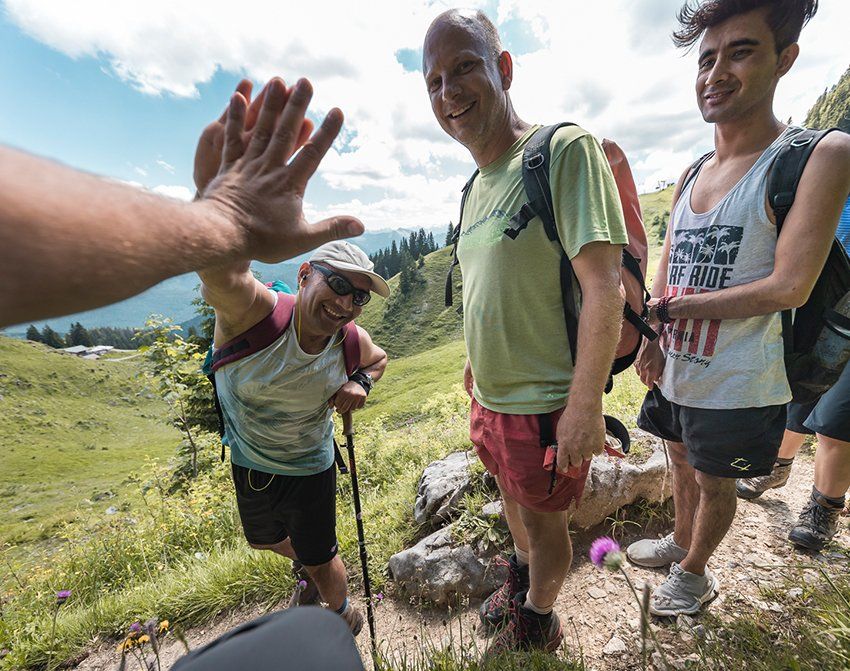 Fröhlicher Teilnehmer einer Alm-Tour klatschen sich mit den Händen ab.