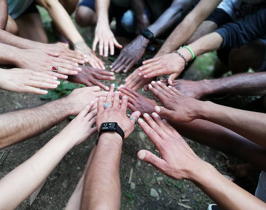 Teilnehmer einer ALM-Tour strecken die Hände zusammen. Es sind die Hände unterschiedlichster Menschen zu sehen.