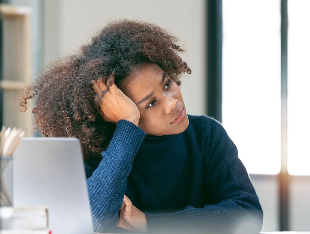 Eine Frau sitzt am Arbeitsplatz und träumt vor sich hin