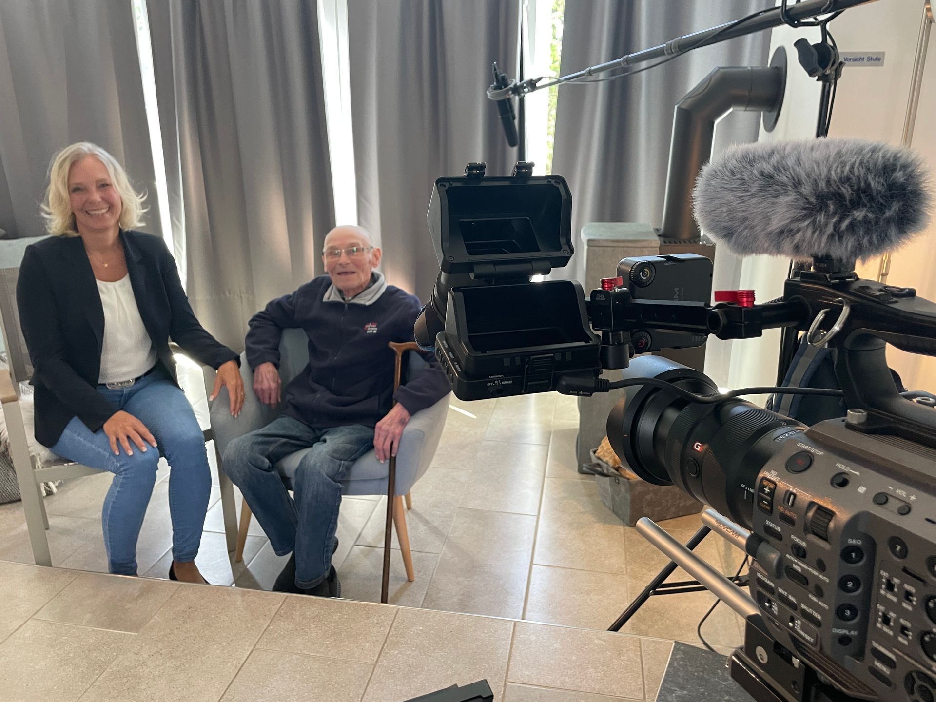Mit Kamera und Mikro im Einsatz – und einem Blick, der mehr Fragen aufwirft als Antworten gibt.
Dreharbeiten mit Augenzwinkern – manchmal sagt ein Bild mehr als tausend Worte. Nadine Witt mit Zeitzeuge Hans Grunst mit einem Kamerateam bei Dreharbeiten.