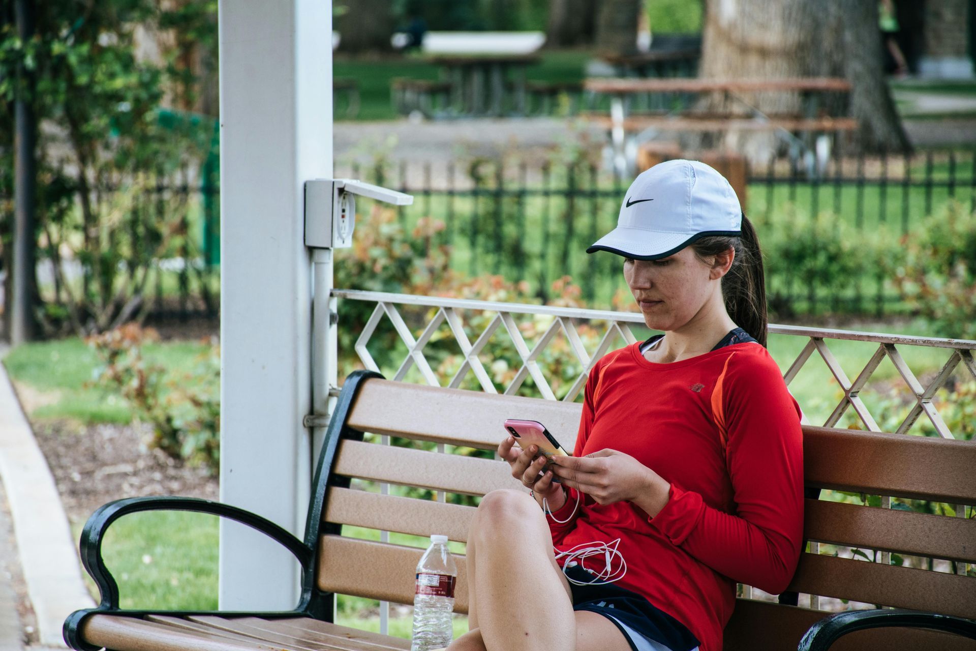 woman sitting on a bench in sport gear on her phone