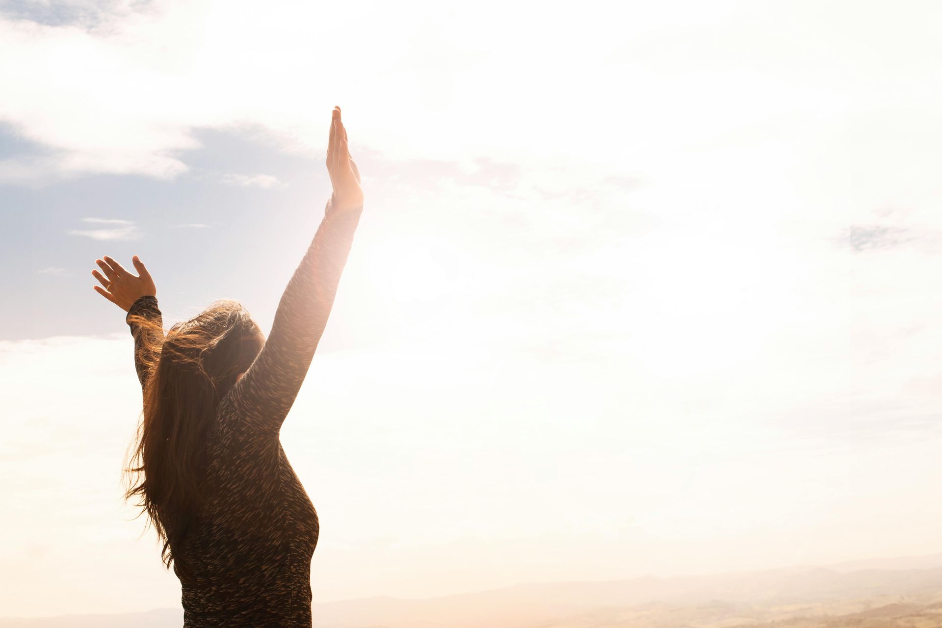 women reaching hands up into the sunset looking free