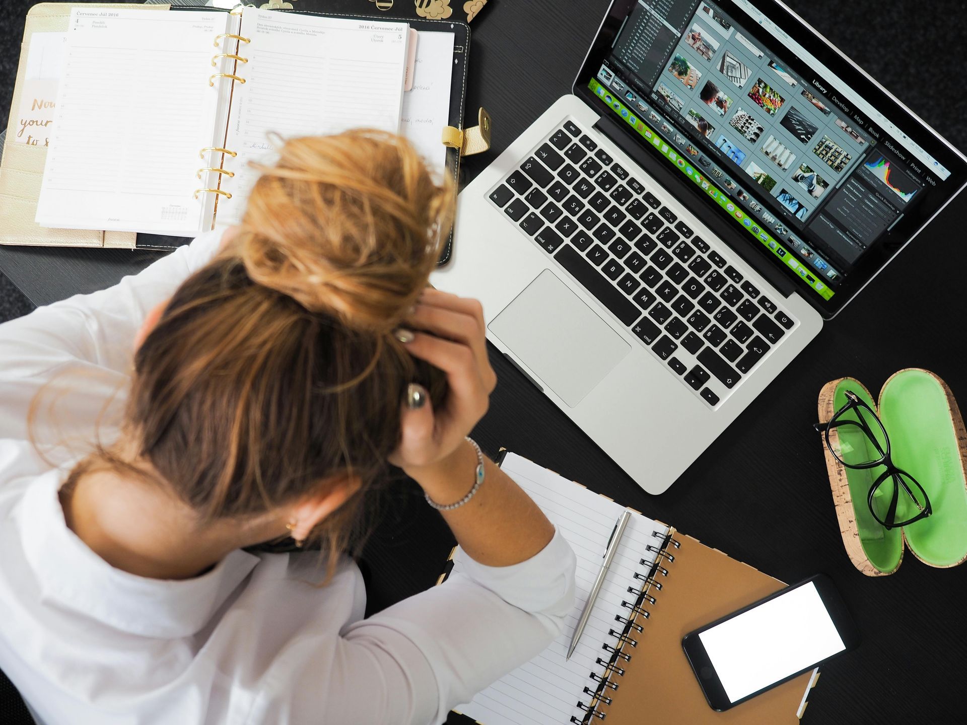 Woman sitting at a desk in front of laptop head in hands