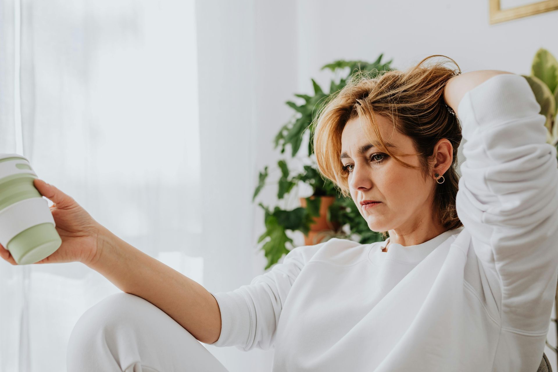 woman wearing a white jumper holding a coffee