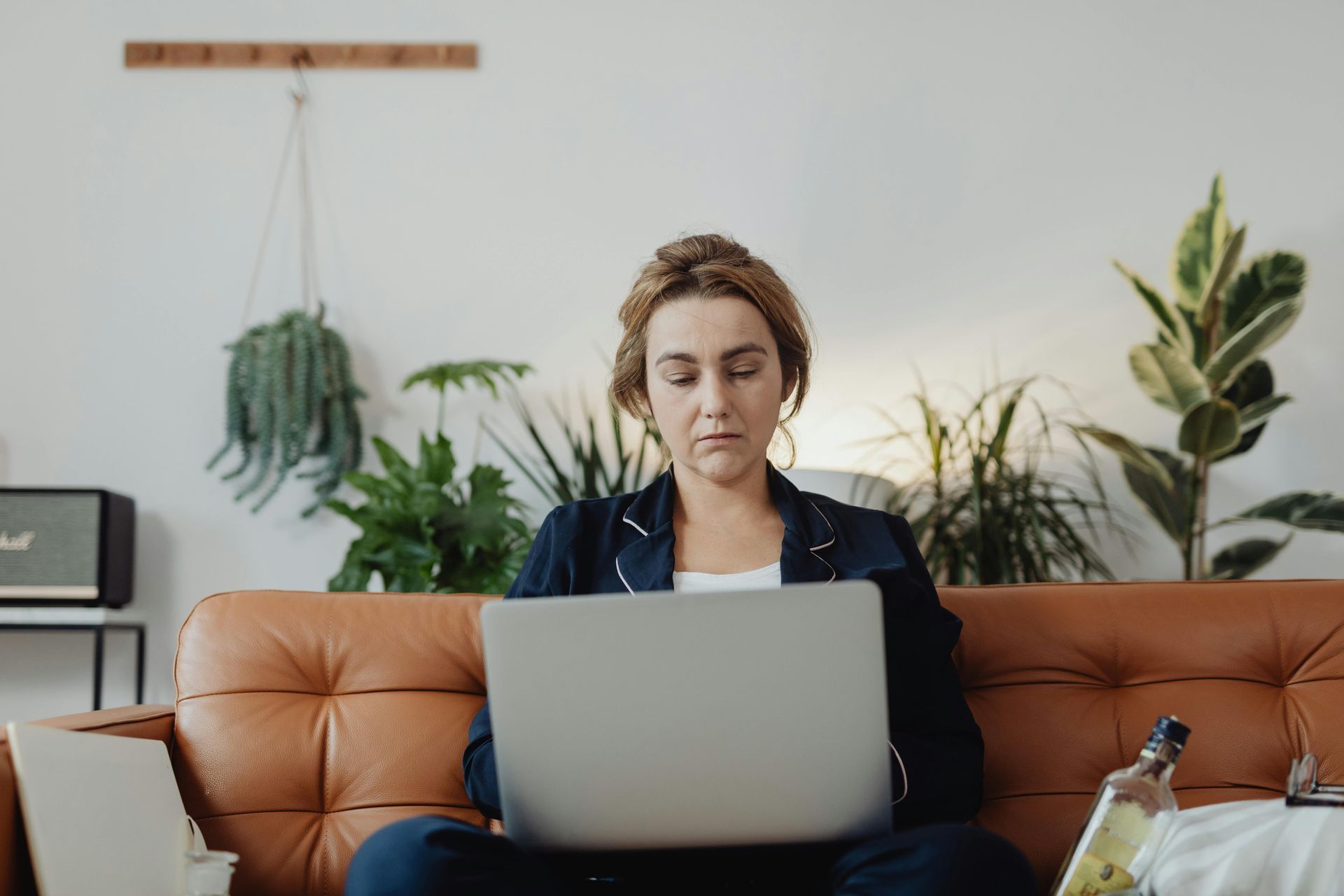 woman sitting on brown sofa looking at laptop