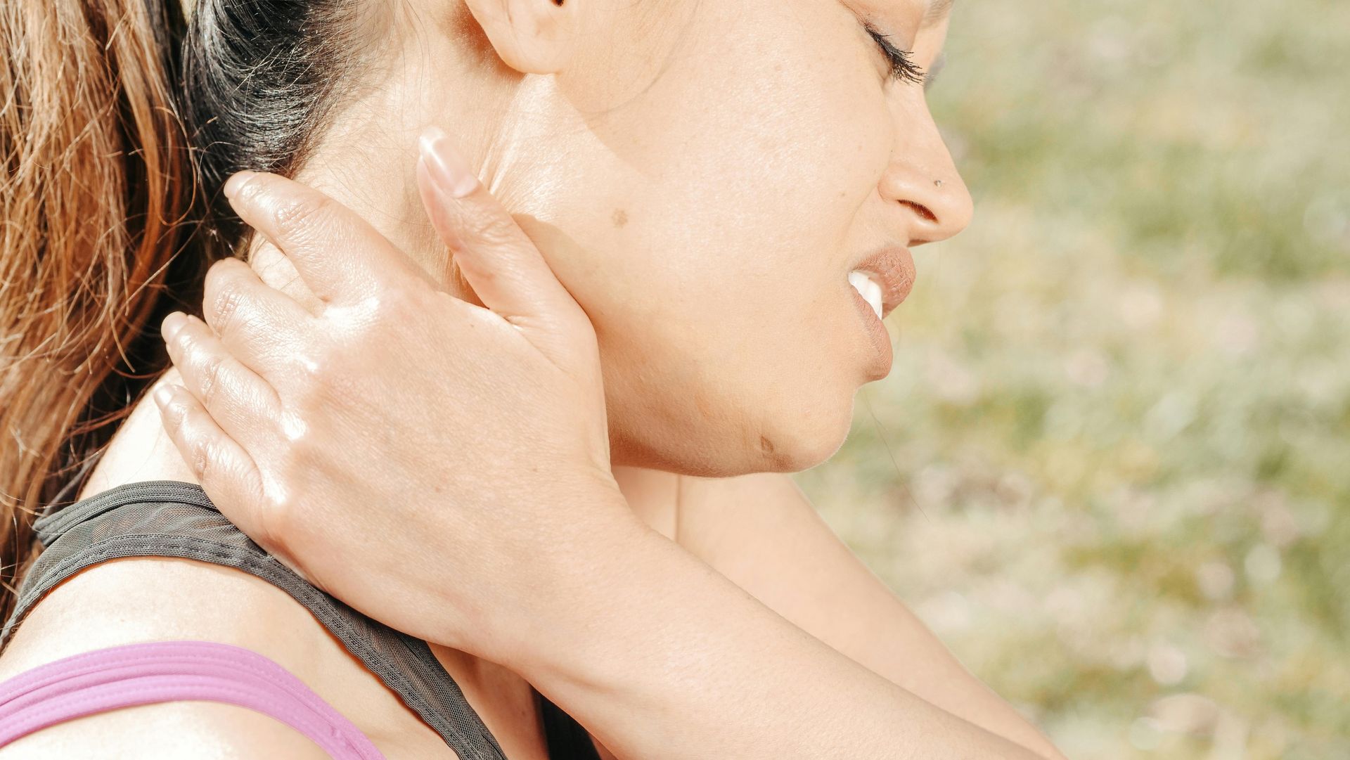 woman holding neck looking in pain