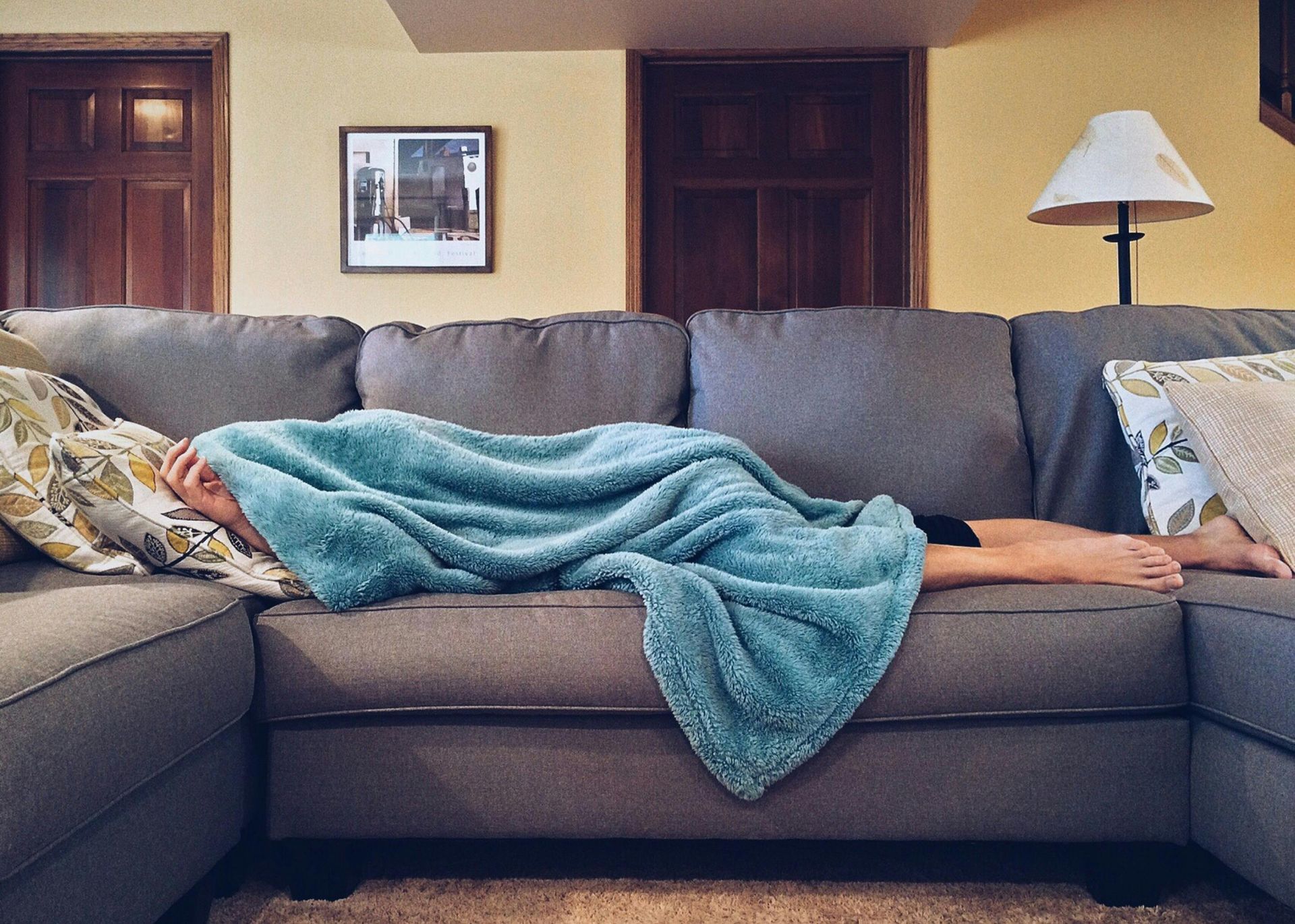 person laying on sofa under a blanket