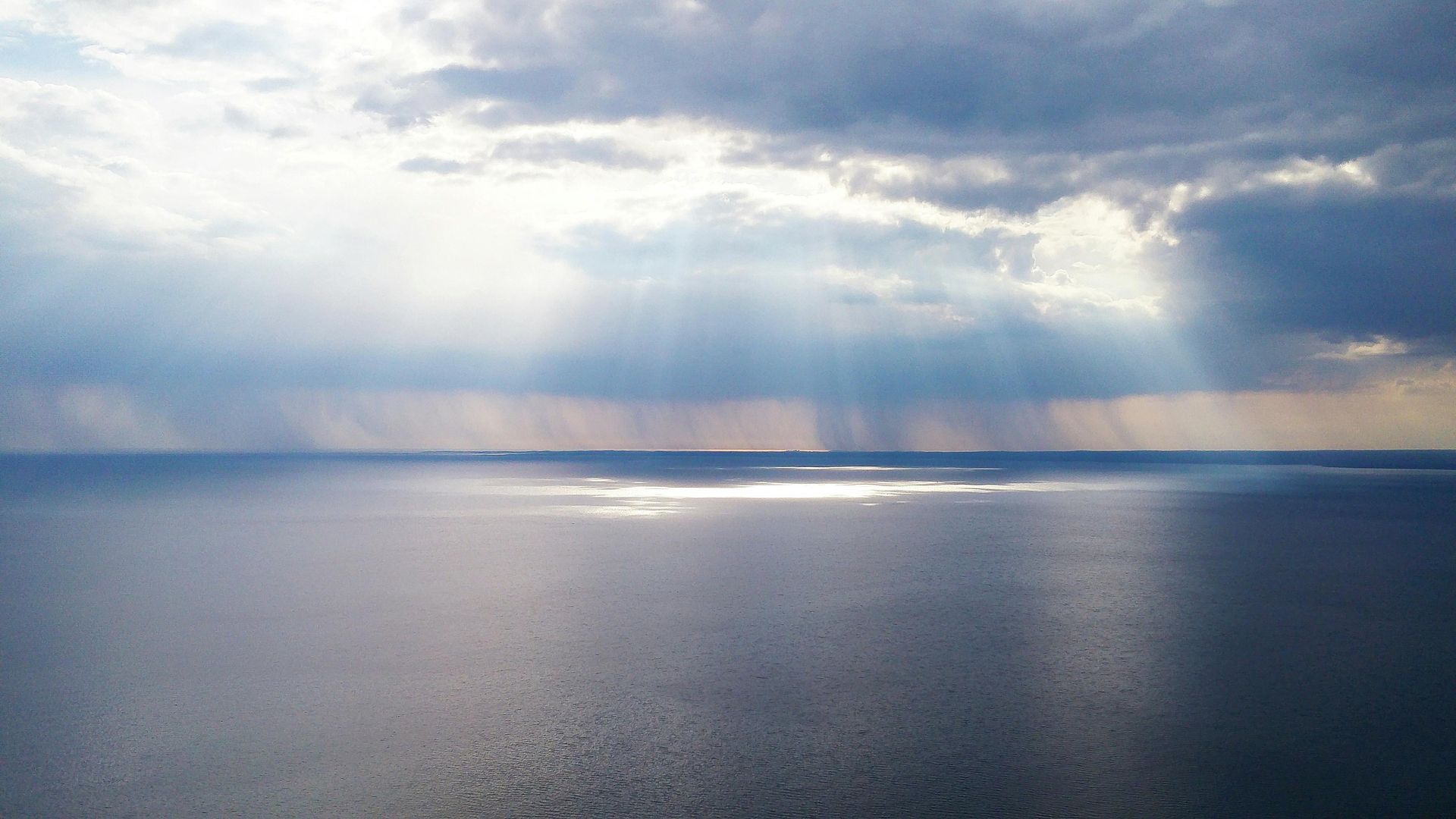 Calm sea with clouds in the sky and  sunlight beaming down in rays through the clouds