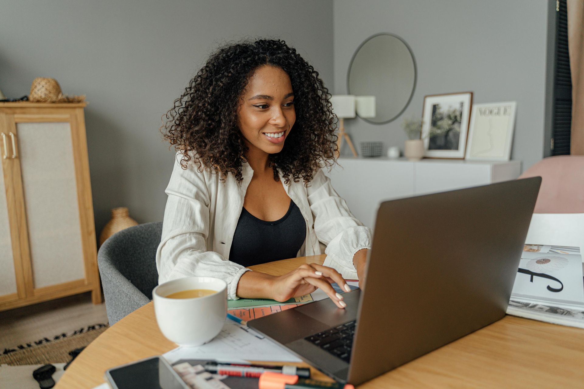 women sitting at table in front of laptop with a cup of tea