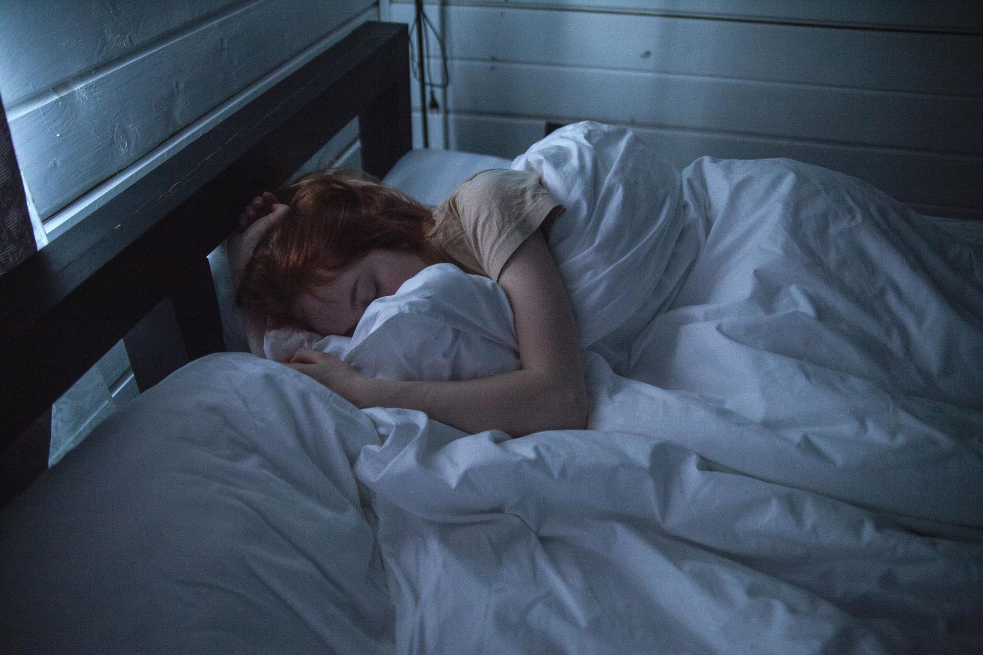 women in bed in the dark face under covers unable to sleep