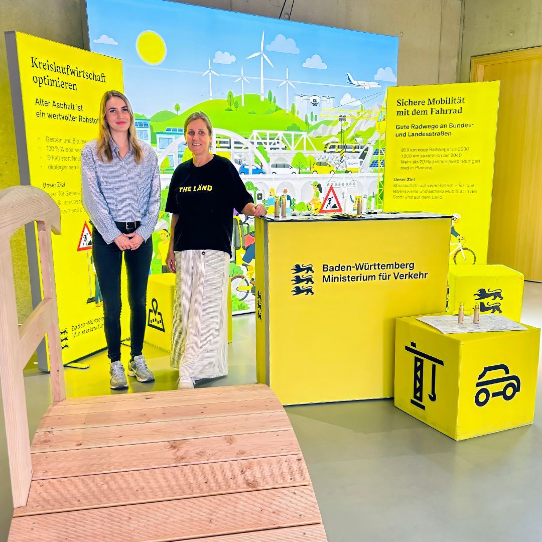 Das Bild zeigt zwei Frauen vor einem Messestand des Verkehrsministeriums