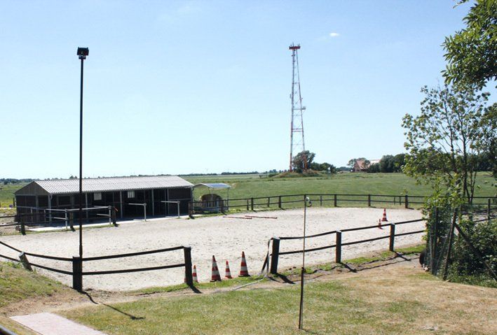 Der Pferdestall und davor der Reitplatz