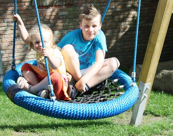 Mädchen und Junge schaukeln in einer Nestschaukel