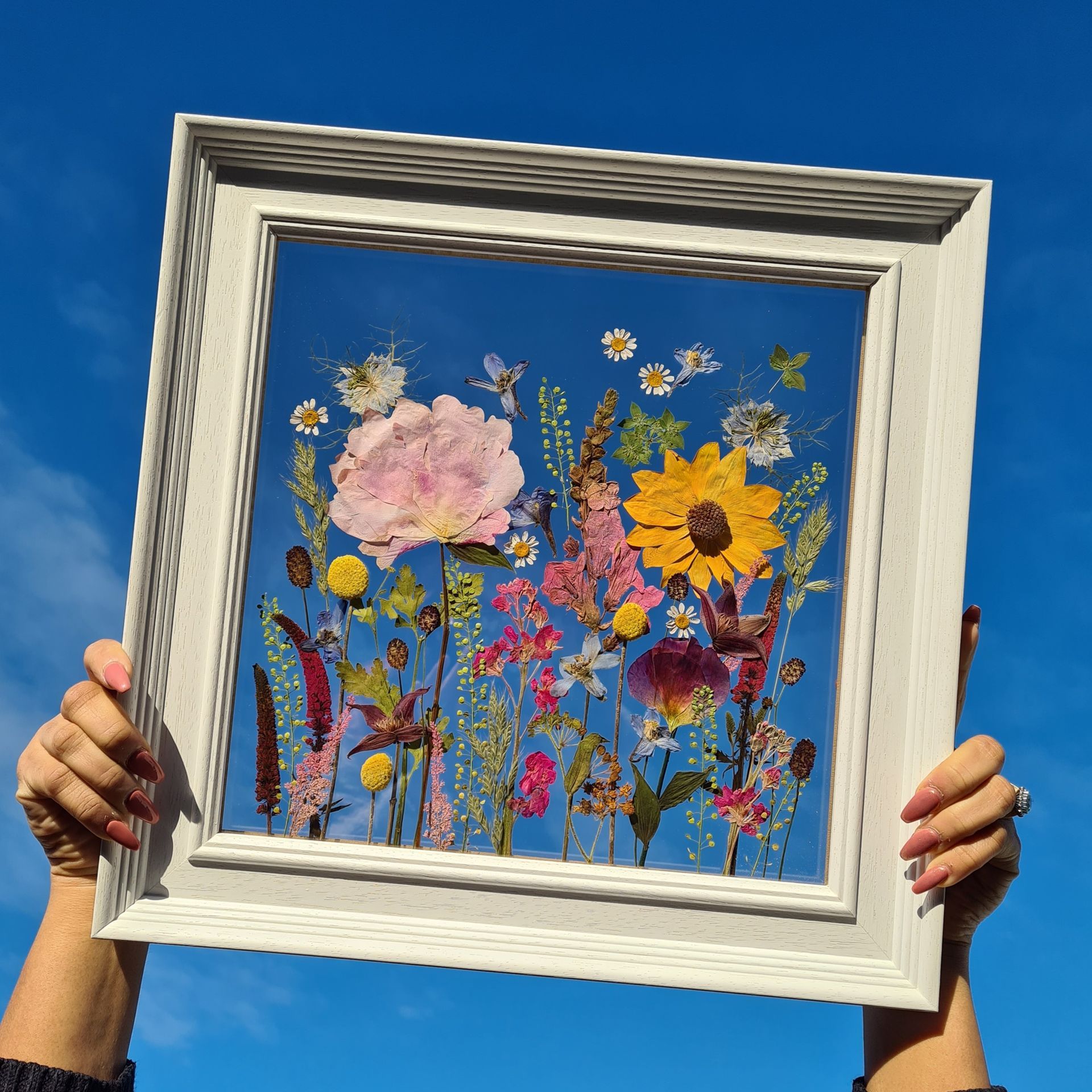 Pressed wedding flowers in a white frame see through frame.