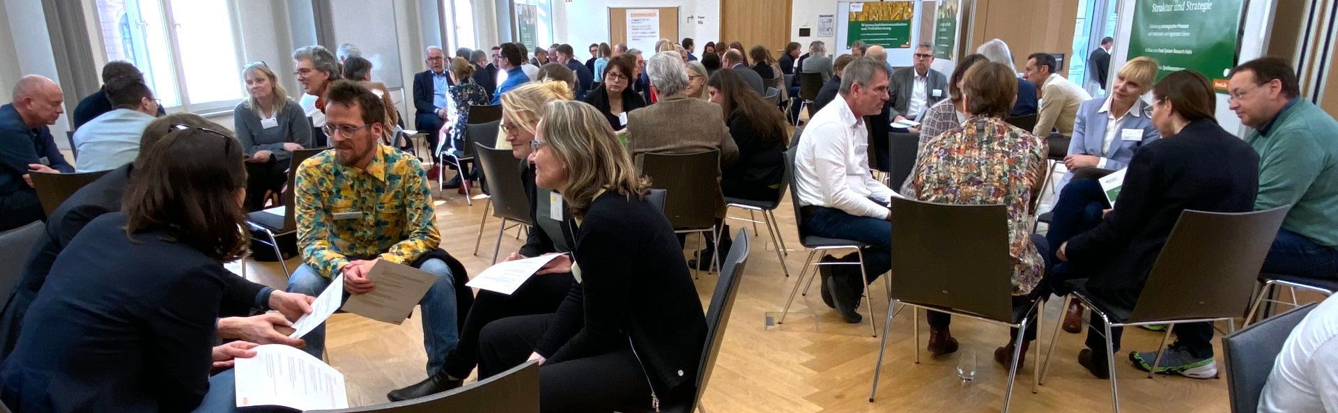 Kleingruppen in aufmerksamem Gespräch Vertreter von Wissenschft und Politik diskutieren, wie ein Systemwandel im Agrar, Lebensmittel- und Ernährungssystem erfolgen könnte