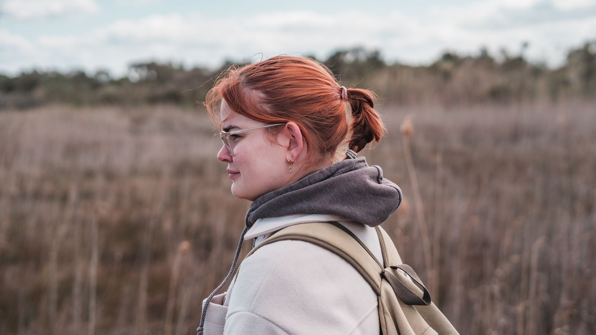 Junge Frau mit Rucksack in einem Park schaut zur Seite, Bild von Fotograf Hannes Schmidt