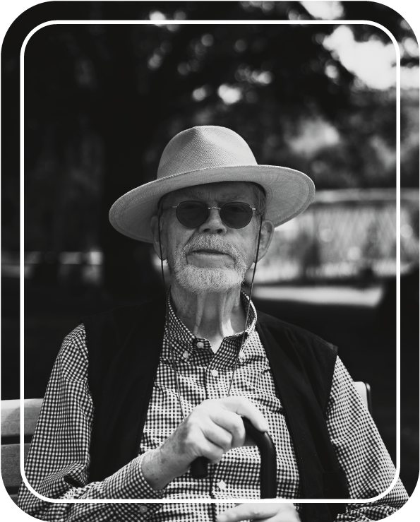 Älterer Mann in Hut und Hemd mit Brille schaut neutral in die Kamera, Bild von Fotograf Hannes Schmidt