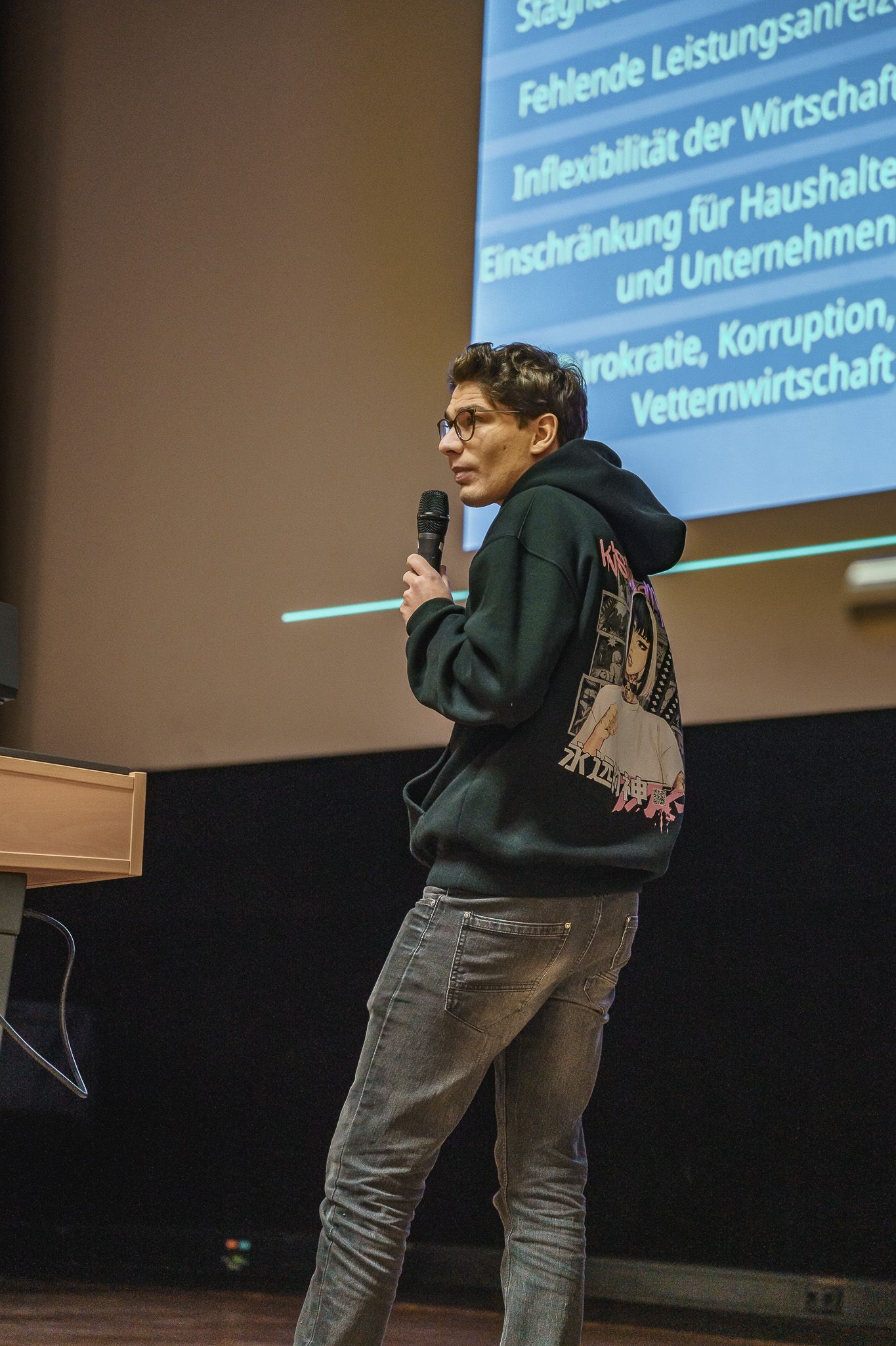 Vortrag mit Mikrofon auf einer Bühne bei der PowerPoint Karaoke von Fotograf Hannes Schmidt in Aachen
