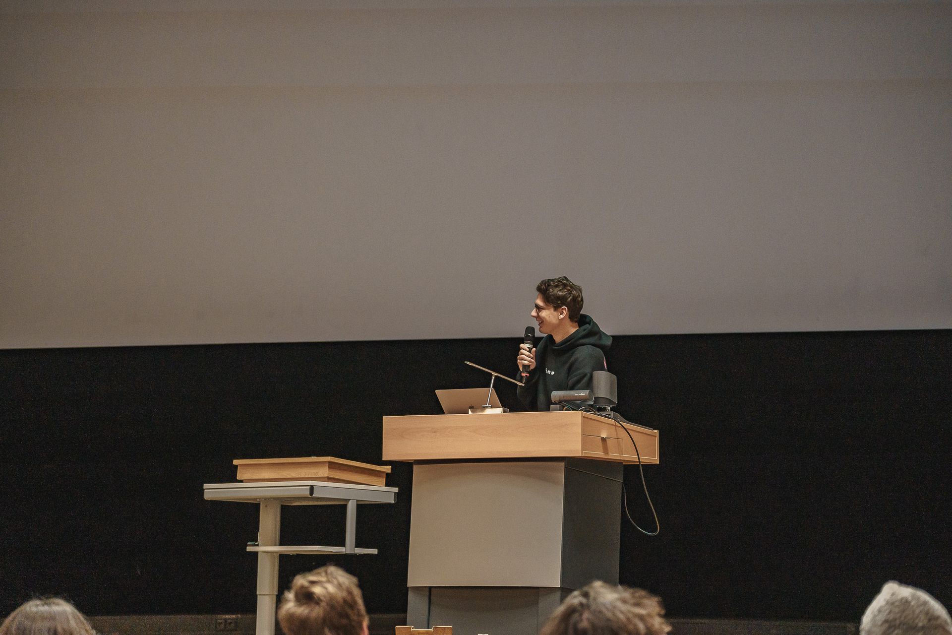 Vortragender auf der Bühne vor einem Pult bei der PowerPoint Karaoke von Fotograf Hannes Schmidt in Aachen