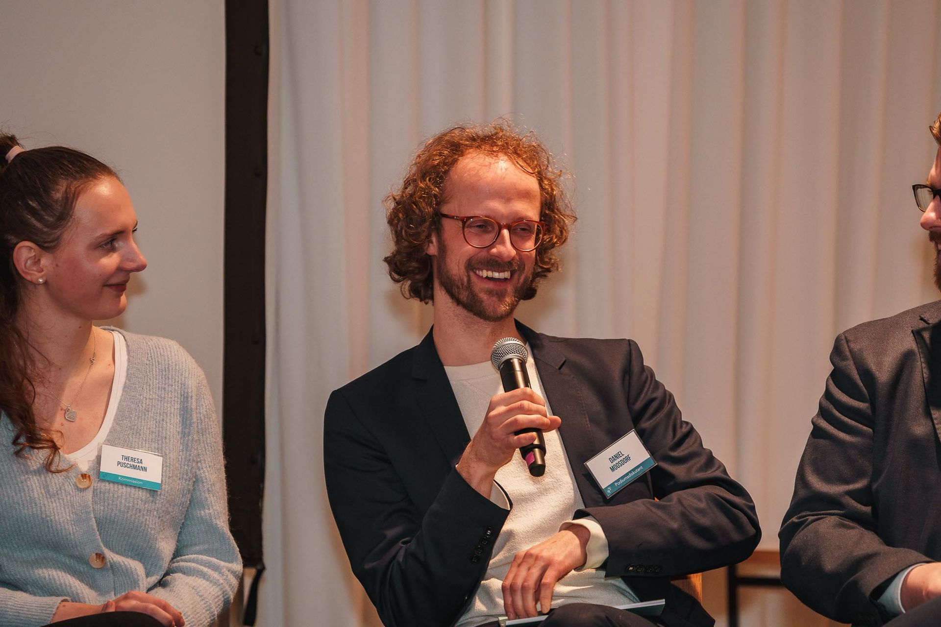 Redner lächelt und spricht in ein Mikrofon, Bild von Fotograf Hannes Schmidt