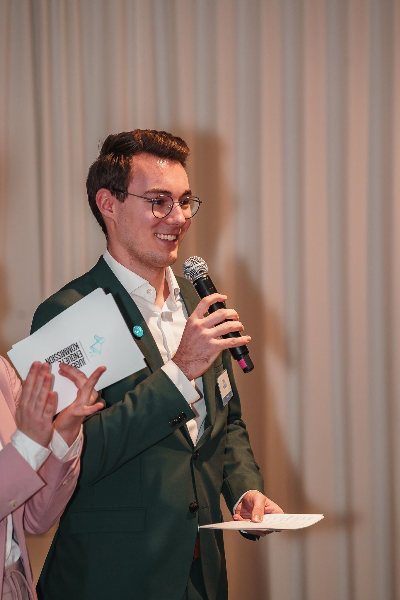 Moderator lächelt ins Publikum mit Mikro, von Fotograf Hannes Schmidt in Aachen