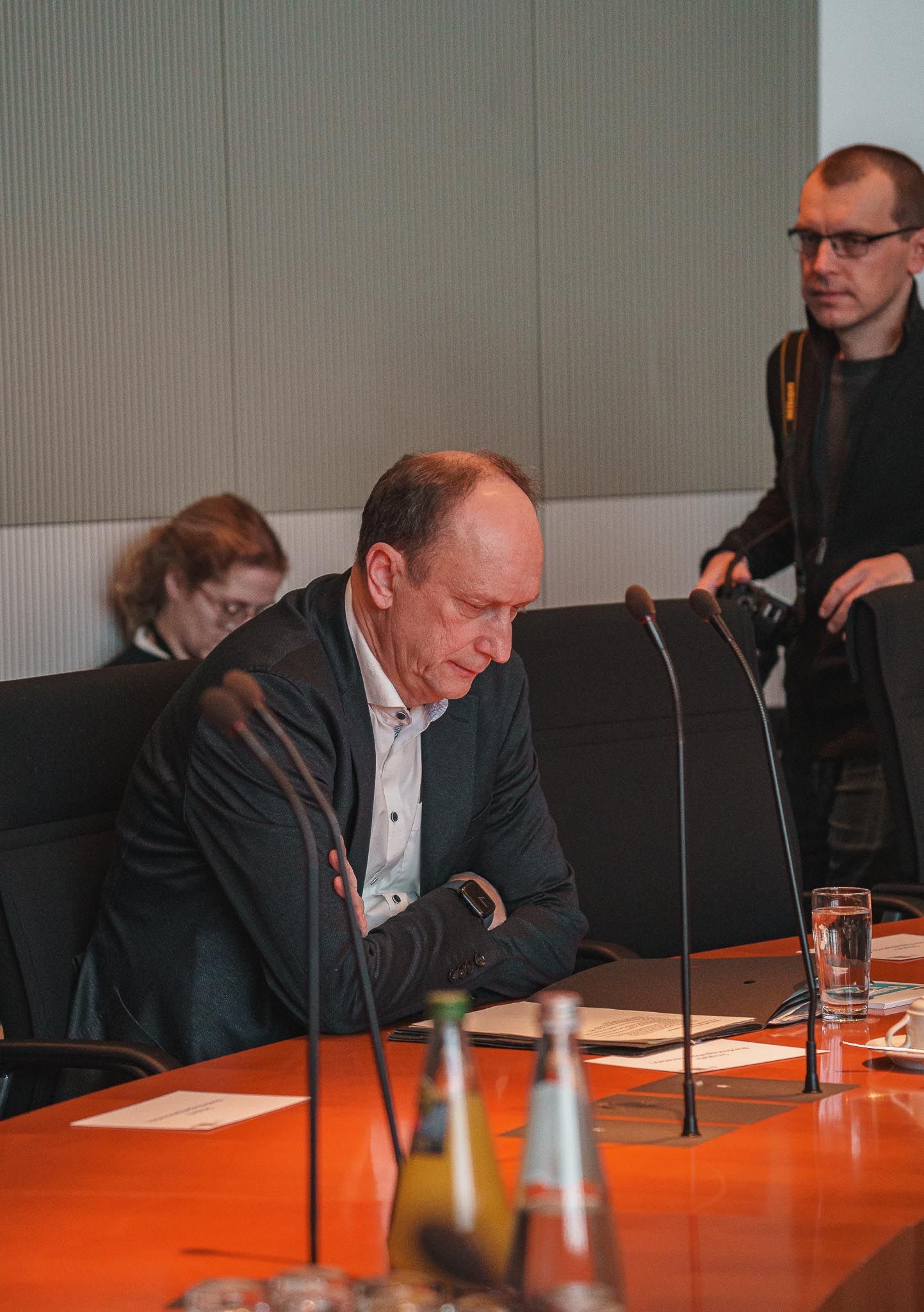 Alter Mann sitzt an einem Tisch vor Mikrofonen,von Fotograf Hannes Schmidt in Aachen