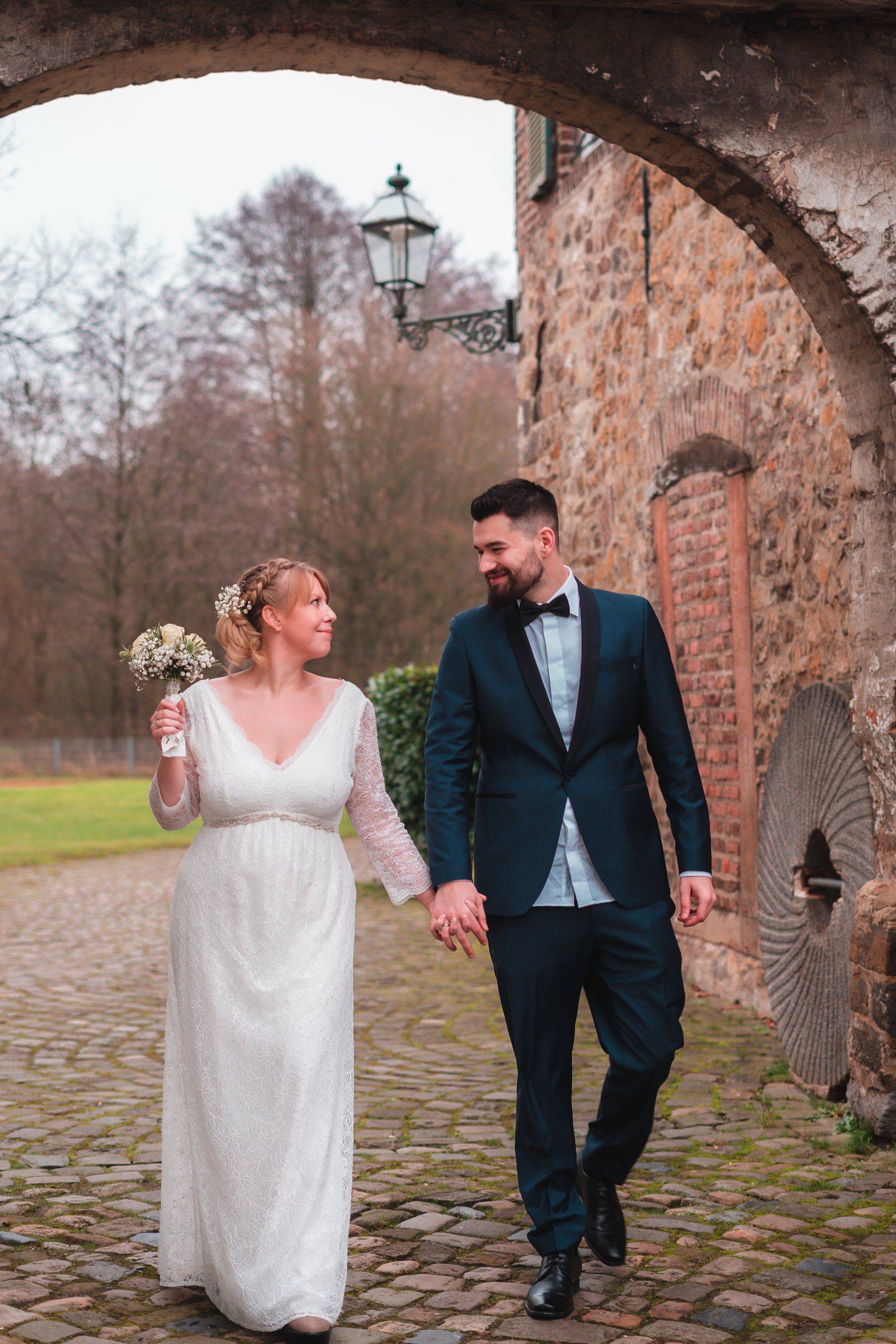 Brautpaar läuft Hand in Hand vor Mühle von Fotograf Hannes Schmidt in Aachen