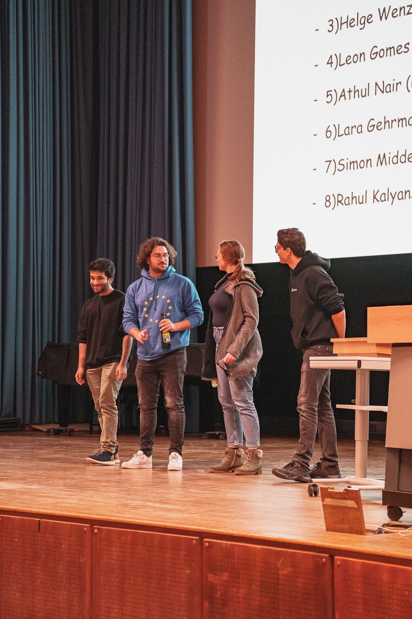 4 Teilnehmer in Reihe auf der Bühne bei PowerPoint Karaoke von Fotograf Hannes Schmidt in Aachen