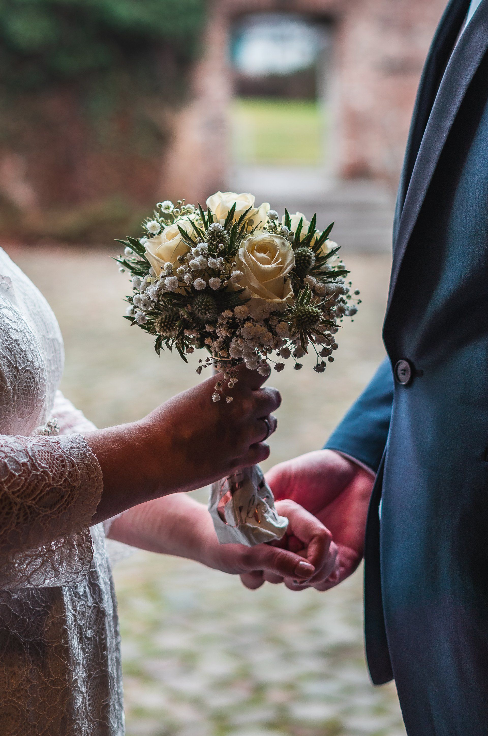 Brautpaar hält vor Tür nach draußen einen Blumenkranz von Fotograf Hannes Schmidt in Aachen