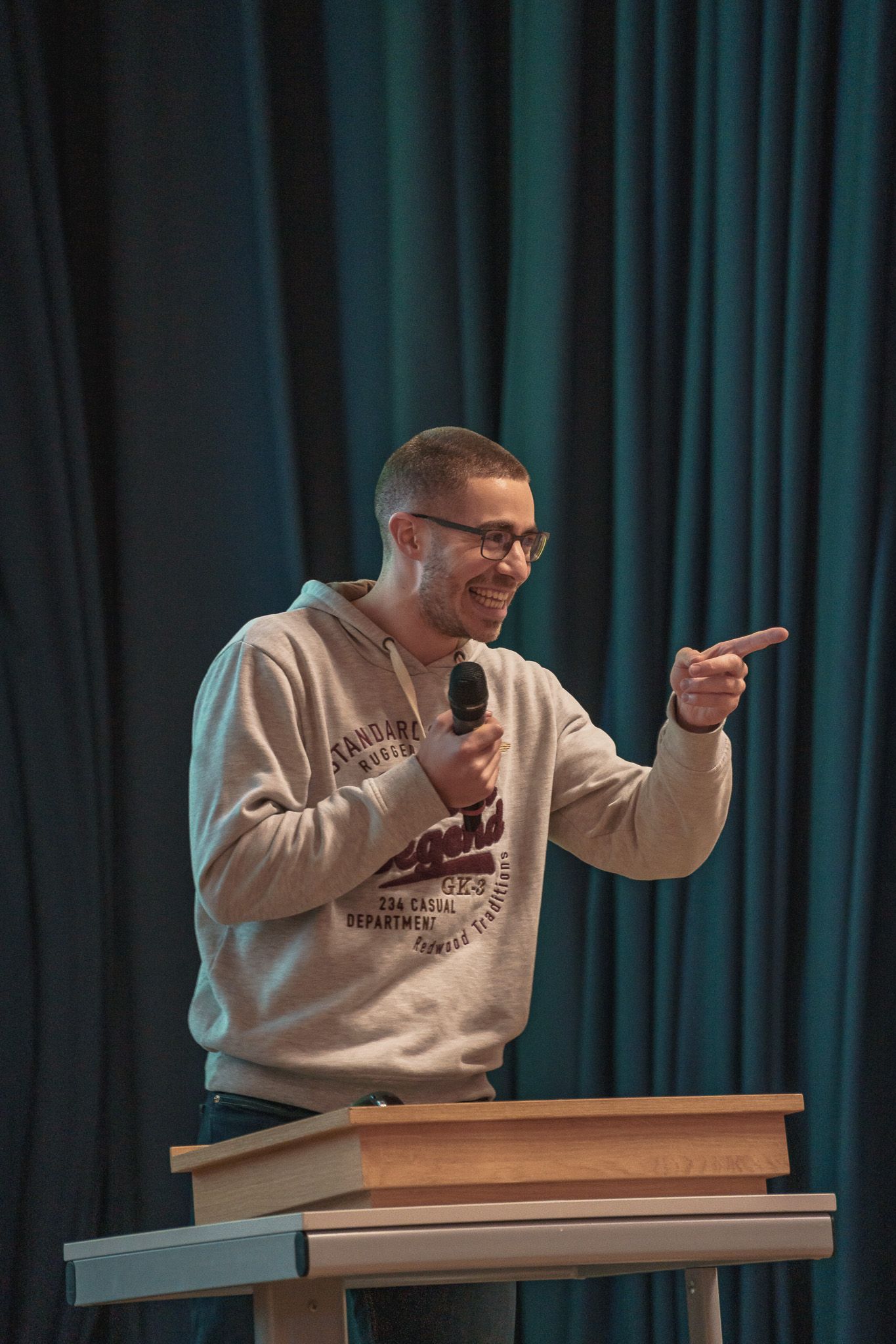 Vortragender lächelnd mit Mikrofon bei der PowerPoint Karaoke von Fotograf Hannes Schmidt in Aachen