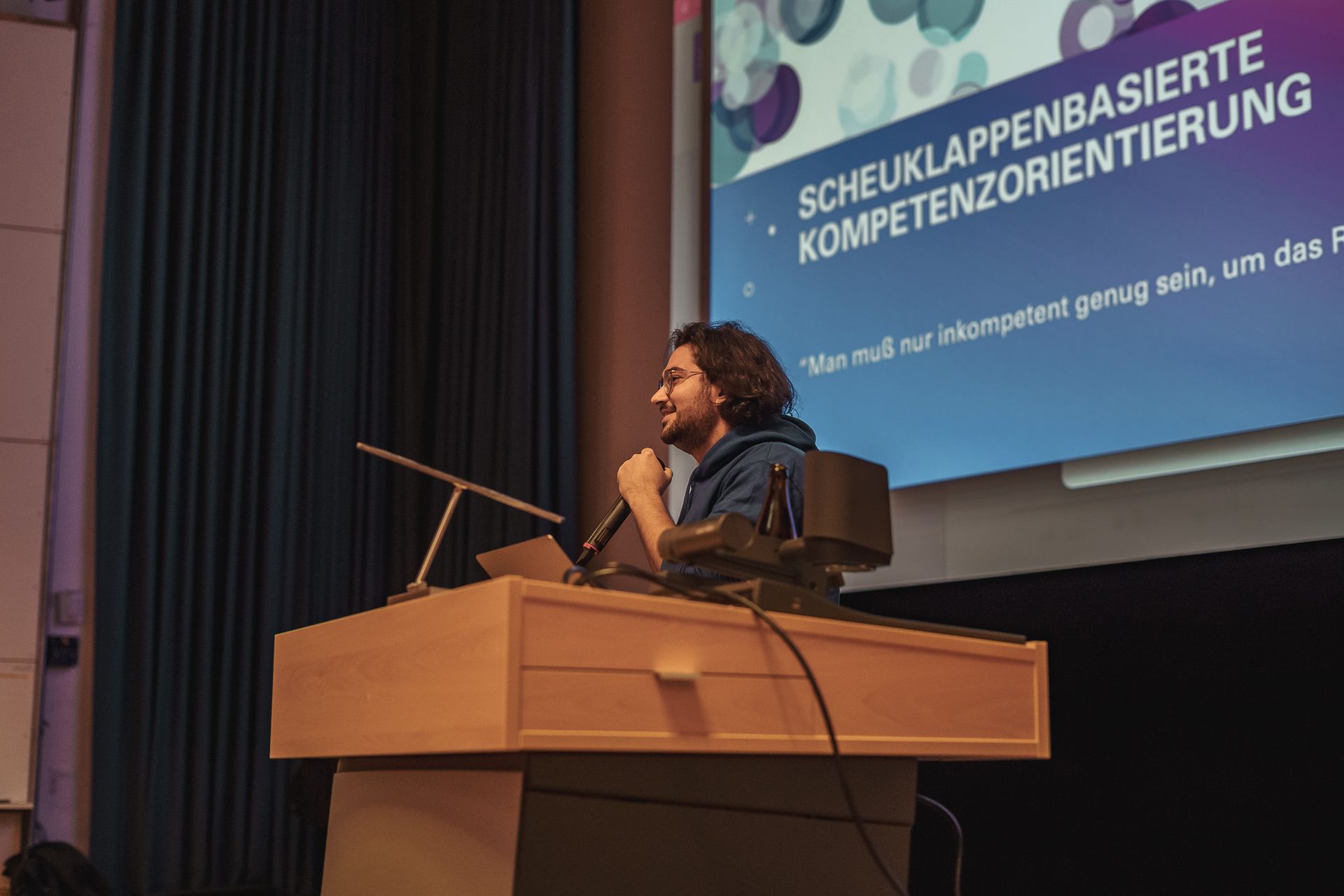 Teilnehmer mit Mikrofon auf der Bühne bei der PowerPoint Karaoke von Fotograf Hannes Schmidt in Aachen