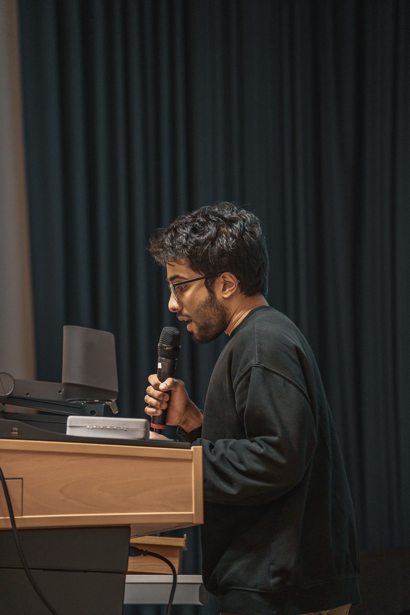 Vortragender mit Mikrofon bei der PowerPoint Karaoke von Fotograf Hannes Schmidt in Aachen