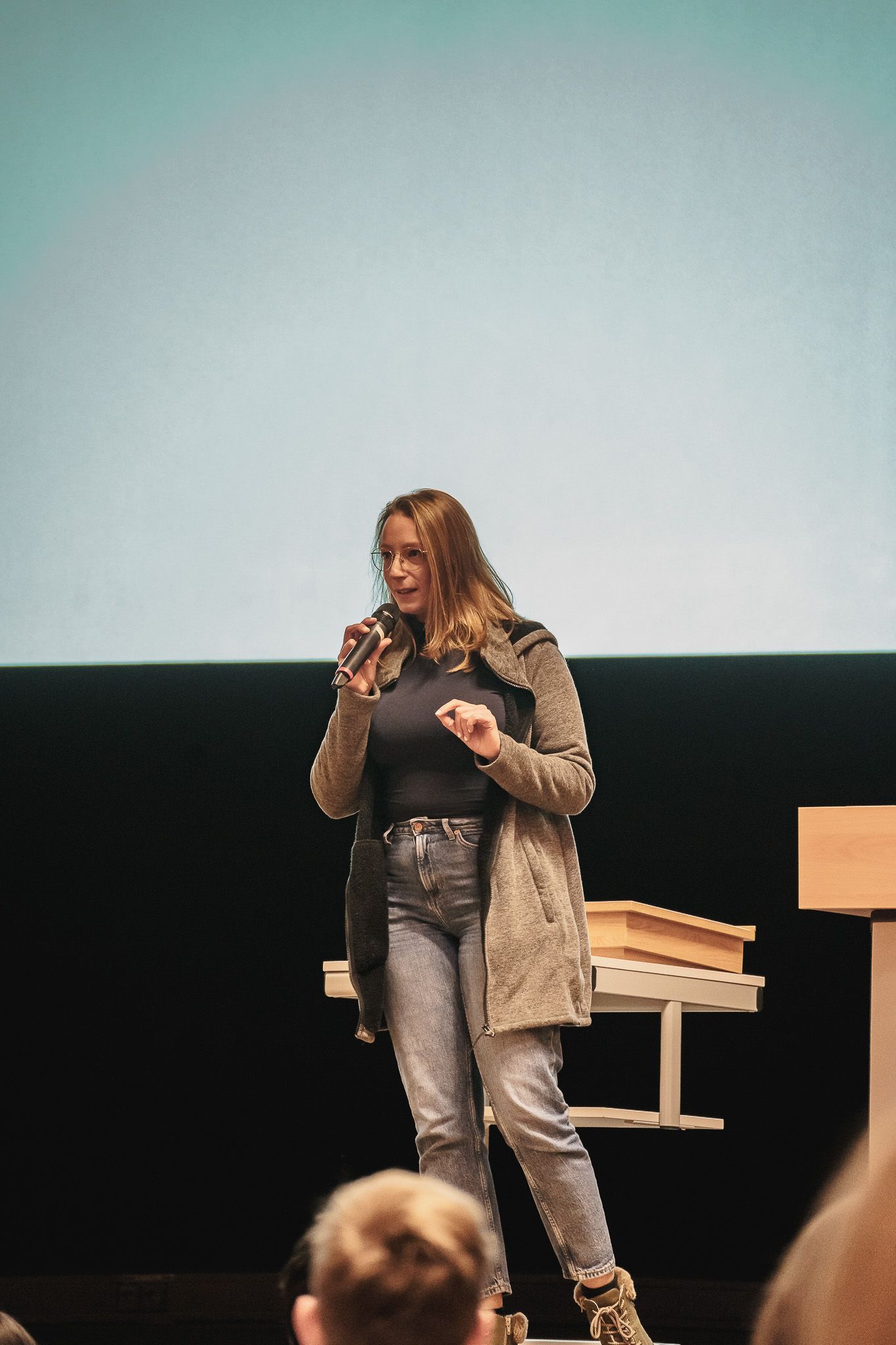 Vortragende mit Mikrofon auf der Bühne bei der PowerPoint Karaoke von Fotograf Hannes Schmidt in Aachen
