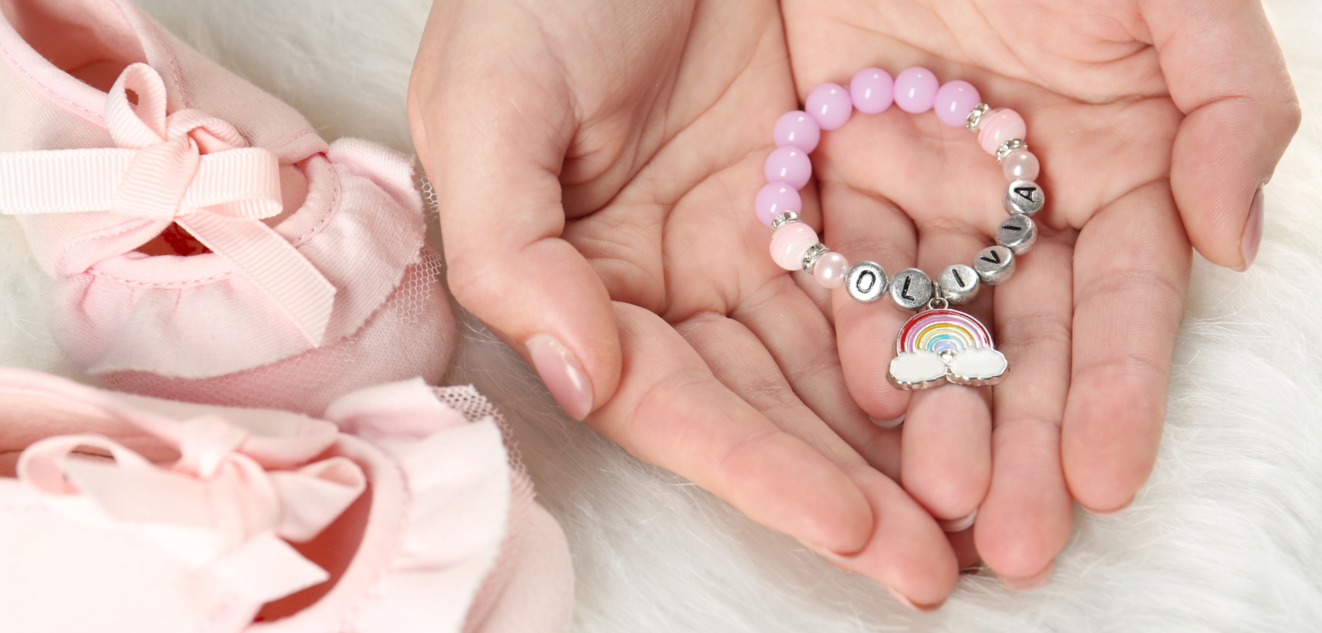 hand holding new born baby bracelet & pink booties