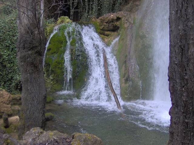 Salto de agua de la Cascada de Fuentetoba sobre la piedra toba y musgo en Soria.