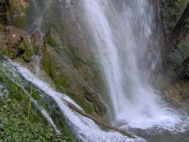 Salto de agua de la Cascada de Fuentetoba sobre la piedra toba y musgo en Soria.